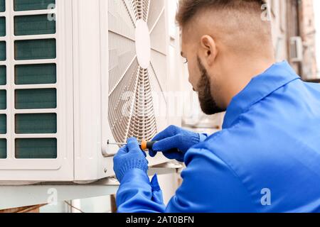 Male technician installing outdoor unit of air conditioner Stock Photo