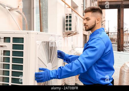 Male technician installing outdoor unit of air conditioner Stock Photo
