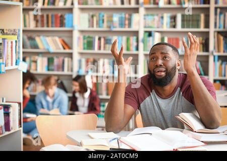 Stressed African-American student preparing for exam in library Stock Photo