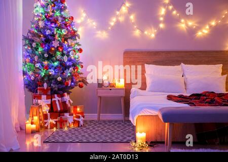 Interior of bedroom with beautiful decorated Christmas tree at night Stock Photo