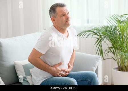 Mature man suffering from abdominal pain at home Stock Photo