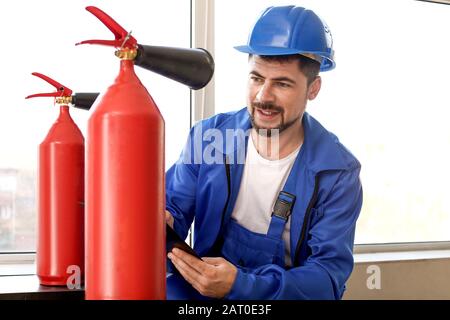 Fire safety specialist inspecting extinguisher Stock Photo