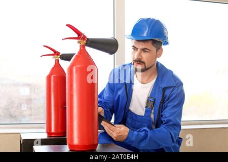 Fire safety specialist inspecting extinguisher Stock Photo