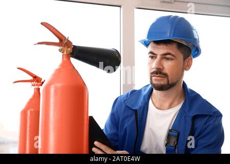Fire safety specialist inspecting extinguisher Stock Photo