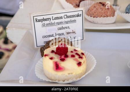 Raspberry lemon cheesecake on display at a homemade food stand at the local farmer's market. Frosting with raspberry on top. Sign with ingredients.  Stock Photo