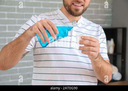 Handsome young man with mouth rinse in bathroom Stock Photo
