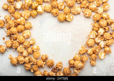 Heart shape made of tasty popcorn on light background Stock Photo