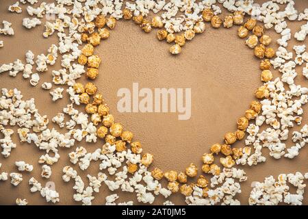 Heart shape made of tasty popcorn on color background Stock Photo