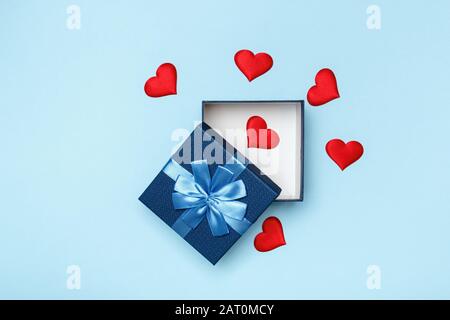 The concept of love and Valentine's Day. Open gift box and red hearts on a blue background. Stock Photo