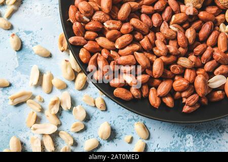 Plate with peanuts on color background Stock Photo