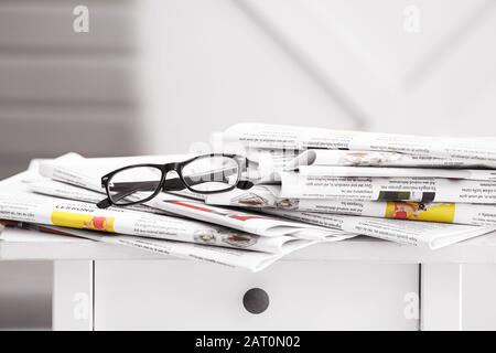 Stack of newspapers on table in room Stock Photo