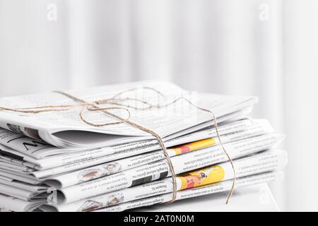Stack of newspapers on table in room Stock Photo