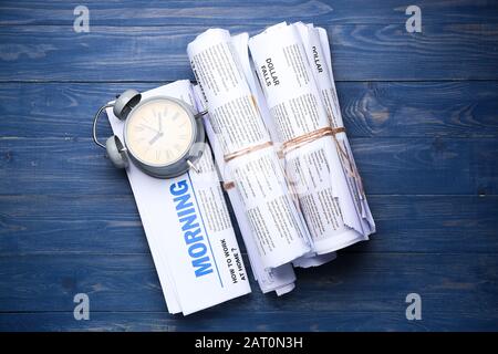 Newspapers and clock on wooden background Stock Photo