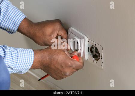 African-American electrician replacing socket in room, closeup Stock Photo