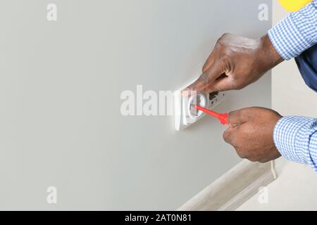 African-American electrician replacing socket in room Stock Photo