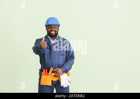 African-American electrician showing thumb-up on color background Stock Photo
