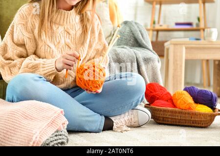 Young woman with knitting yarn and needles at home Stock Photo