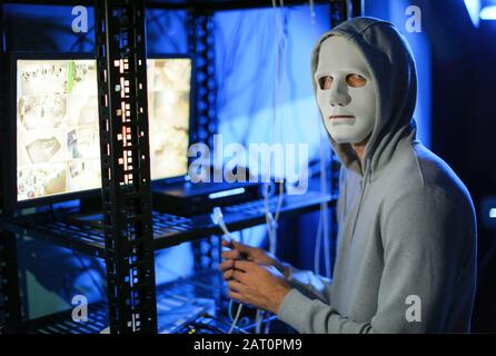 Professional hacker near computer in dark room Stock Photo