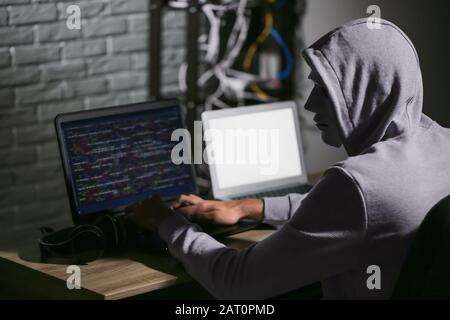 Professional hacker using laptop in dark room Stock Photo
