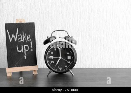 Alarm clock and chalkboard with text WAKE UP on table Stock Photo