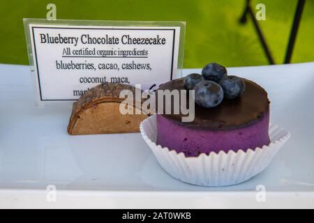 Blueberry chocolate cheesecake at a homemade food stand at the local farmer's market. Glossy frosting with four blueberries on top. Sign with ingredients.  Stock Photo