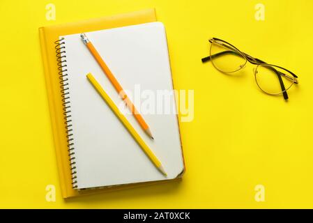 Stylish notebooks with pencils and eyeglasses on color background Stock Photo