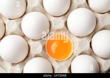 Broken egg among whole ones in box. Concept of uniqueness