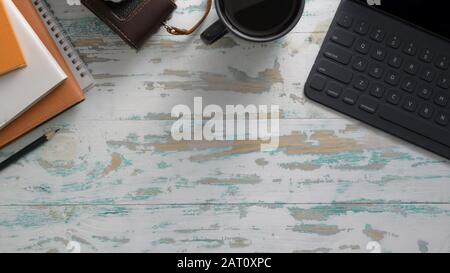Top view of rustic workplace with tablet, camera, office supplies and copy space on vintage table background Stock Photo