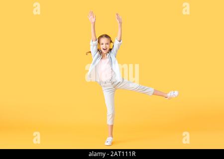 Happy little girl with headphones on color background Stock Photo
