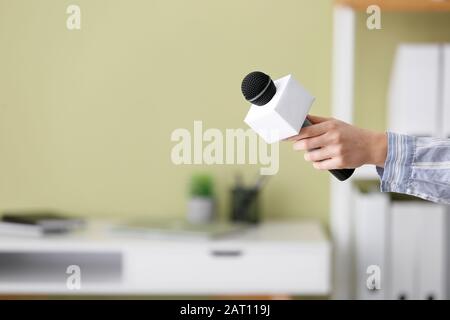 Female journalist with microphone having an interview indoors Stock Photo