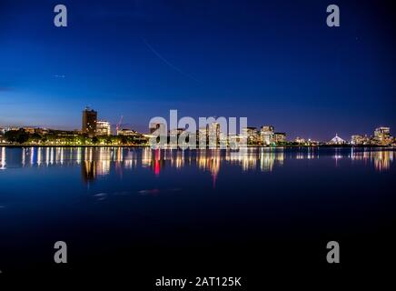 Charles River in Boston reflecting buildings after sunset. City lights and dark blue sky reflected in the river. Stock Photo