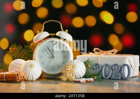 Alarm clock with Christmas decor and gift on table against defocused lights Stock Photo