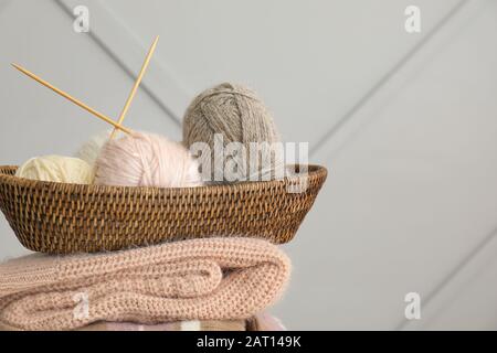 Basket with knitting yarns and clothes on grey background Stock Photo