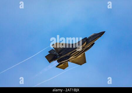 A  Lockheed Martin F-35A Lightning II jet fighter streaks by in the late afternoon sun with afterburner on over Hill Air Force Base near Layton, Utah. Stock Photo