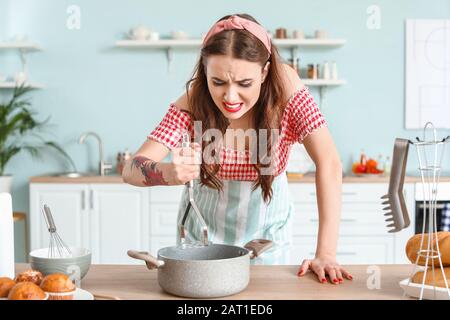 Funny angry housewife cooking in kitchen Stock Photo