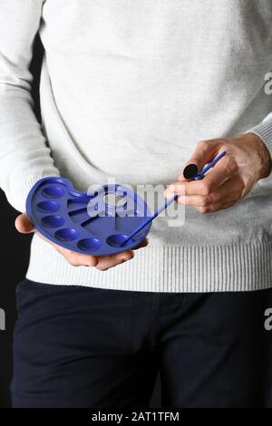 Artist with blue palette and brush on dark background Stock Photo