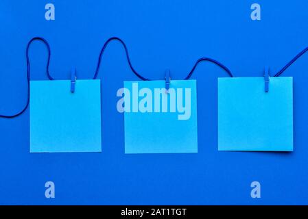 String with blank paper sheets and pegs on blue background Stock Photo