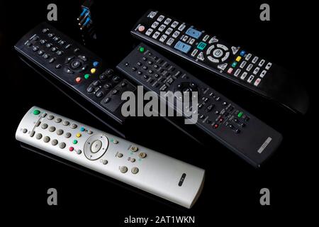 Set of four remote controls on a shiny black background with reflection Stock Photo