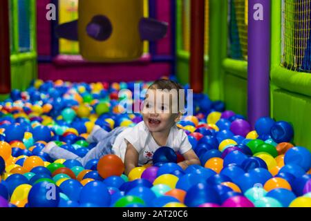 cute and happy little girl laughing and playing in an indoor playground in a shopping mall in Dubai, United Arab Emirates.