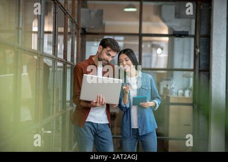 Bearded handsome man in a brown shirt discussing work matters with colleague Stock Photo