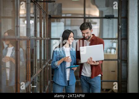 Bearded handsome man in a brown shirt discussing work issues with colleague Stock Photo