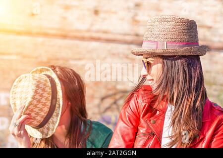 Best hipster friends having fun on sunny day - Happy people joking with fashion hats - Trends lifestyle addiction concept - Soft brown filter with art Stock Photo