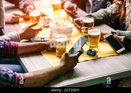 Closeup of hands social networking with mobile phones  - Wifi connected multiracial people in bar table meeting - Concept of teamwork and technology a Stock Photo