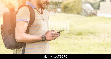 Young Indian man using smartphone outdoor - University student watching videos with mobile phone in school break - New technology trend addiction conc Stock Photo