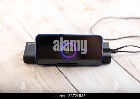 phone being charged with power hub bank on wood background. Stock Photo