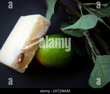 Slice of white handmade soap with almond seed and fresh green lime Stock Photo