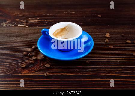 Dirty blue cup after coffee on a wooden table. Near to the cup are coffee beans.  Stock Photo