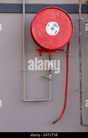 A close up view of a red fire hose mounted on the wall for emergency's Stock Photo