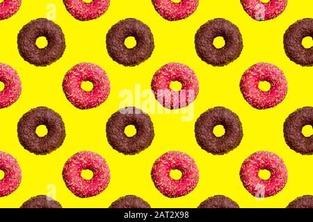 Pattern of pink and chocolate donuts on bright yellow background top view, tasty doughnuts backdrop, colorful sweet dessert wallpaper Stock Photo
