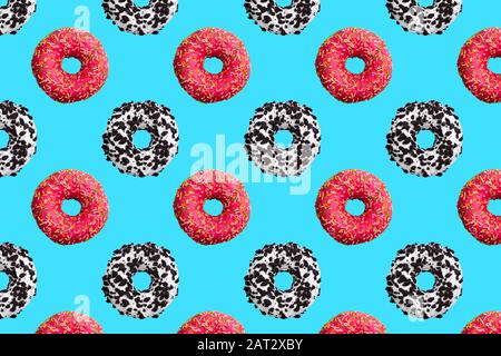 Pattern of pink, white and chocolate donuts on blue background top view, tasty doughnuts backdrop, colorful sweet dessert wallpaper Stock Photo